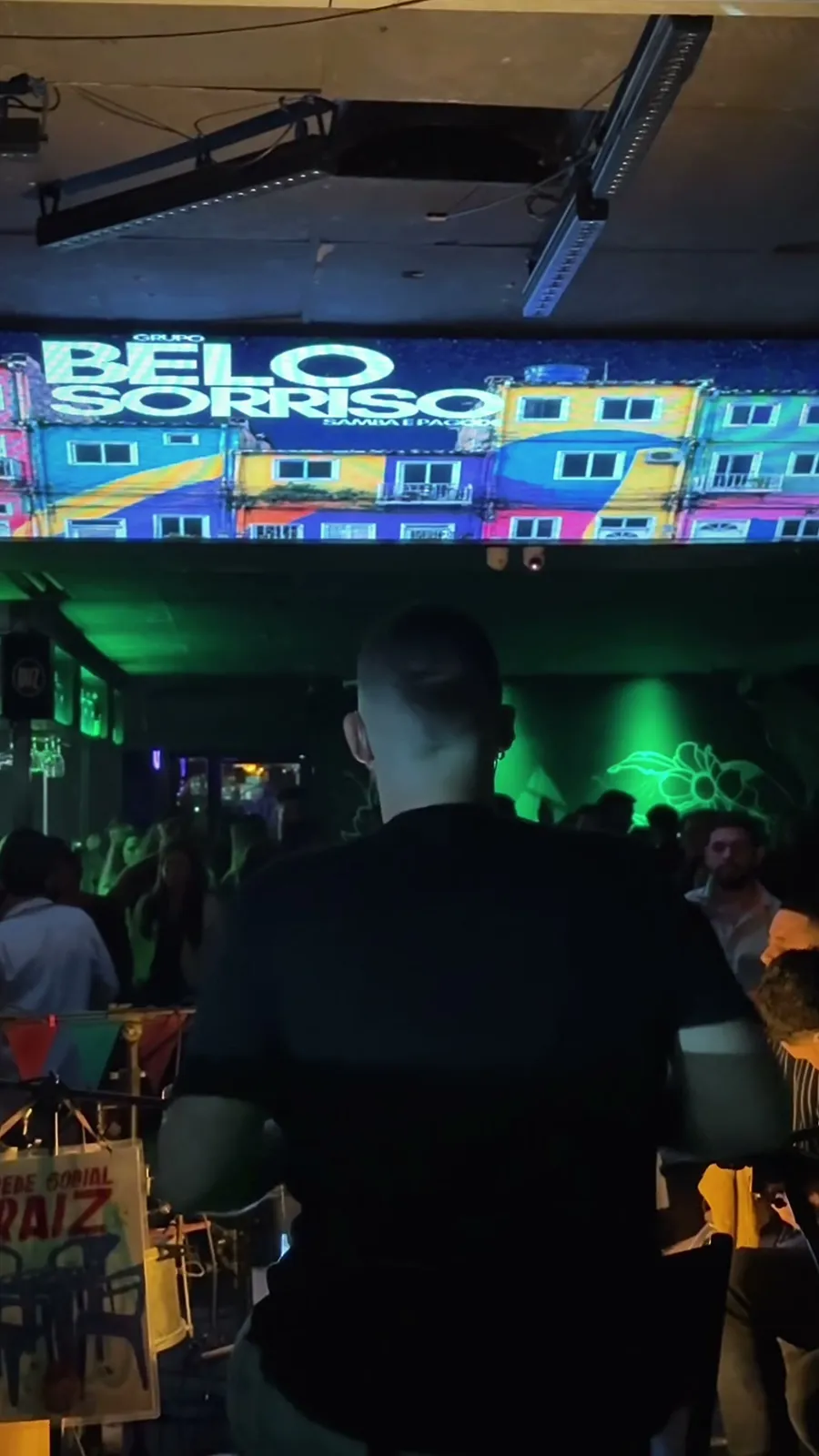 Pantalla con el logo de Grupo Belo Sorriso y el público en Bar Benavidez, en el evento Destino Favela
